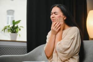 A woman with an abscessed tooth holding her cheek