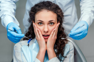 A woman with a chipped tooth looking scared of the dentist