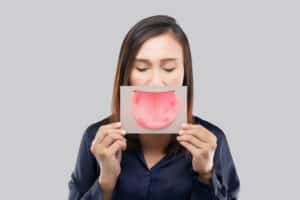 A woman holding an illustration of a tongue with oral cancer sores